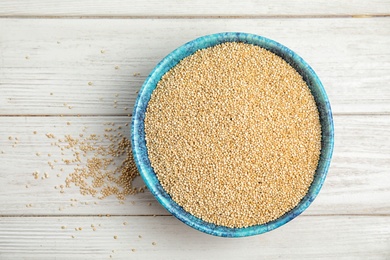 Photo of Bowl with white quinoa on wooden background, top view