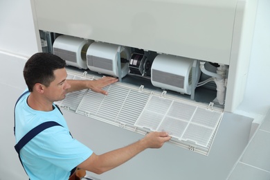 Male technician cleaning air conditioner indoors