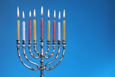 Hanukkah celebration. Menorah with burning candles on blue background, space for text