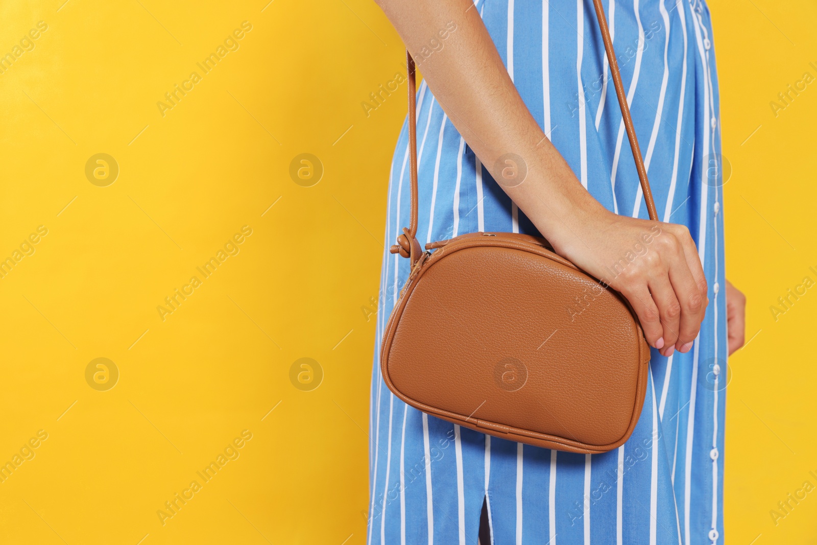 Photo of Woman with stylish bag on orange background, closeup. Space for text