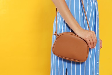 Woman with stylish bag on orange background, closeup. Space for text