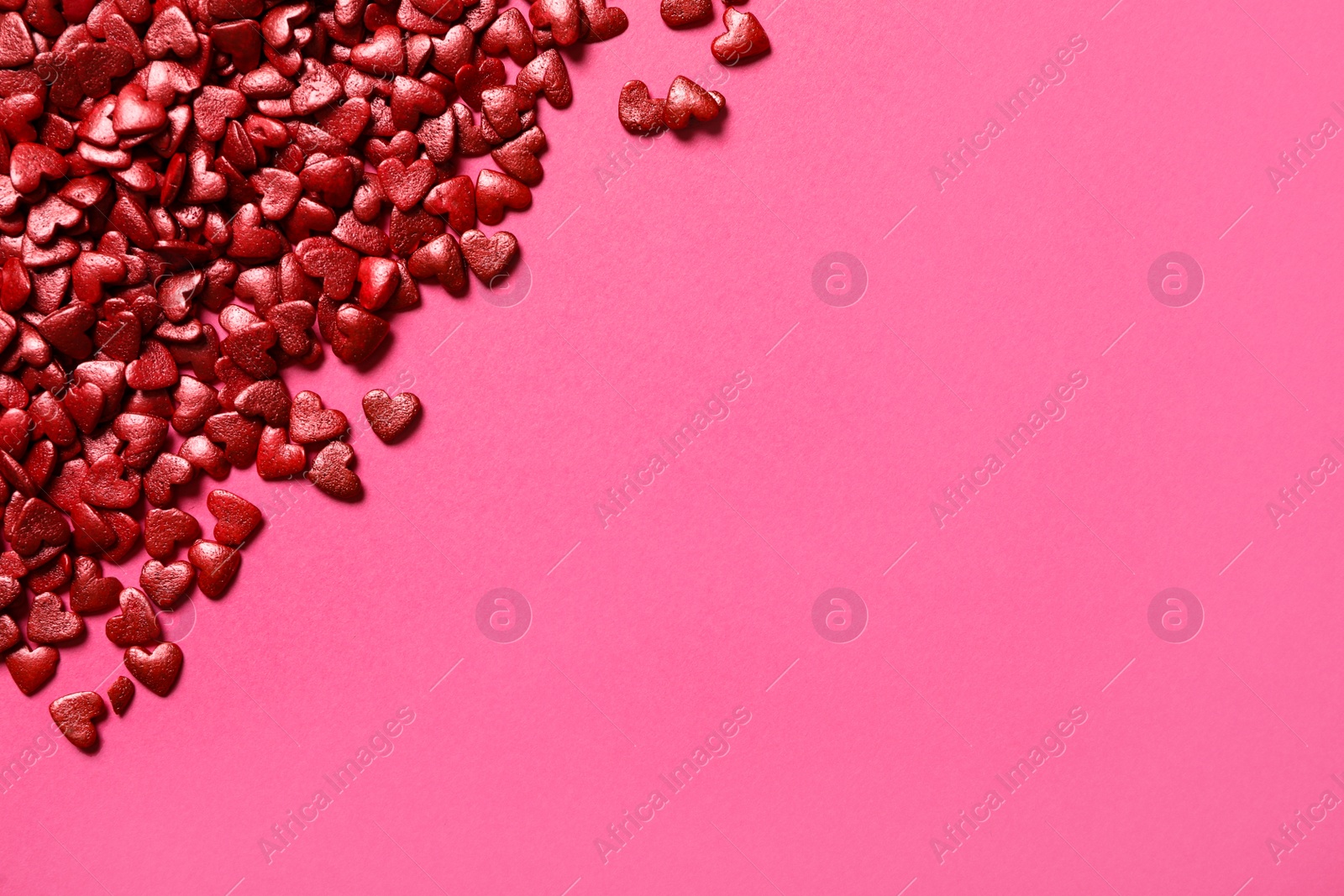 Photo of Red heart shaped sprinkles on pink background, flat lay. Space for text