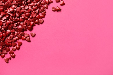 Red heart shaped sprinkles on pink background, flat lay. Space for text