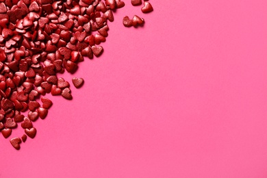 Photo of Red heart shaped sprinkles on pink background, flat lay. Space for text