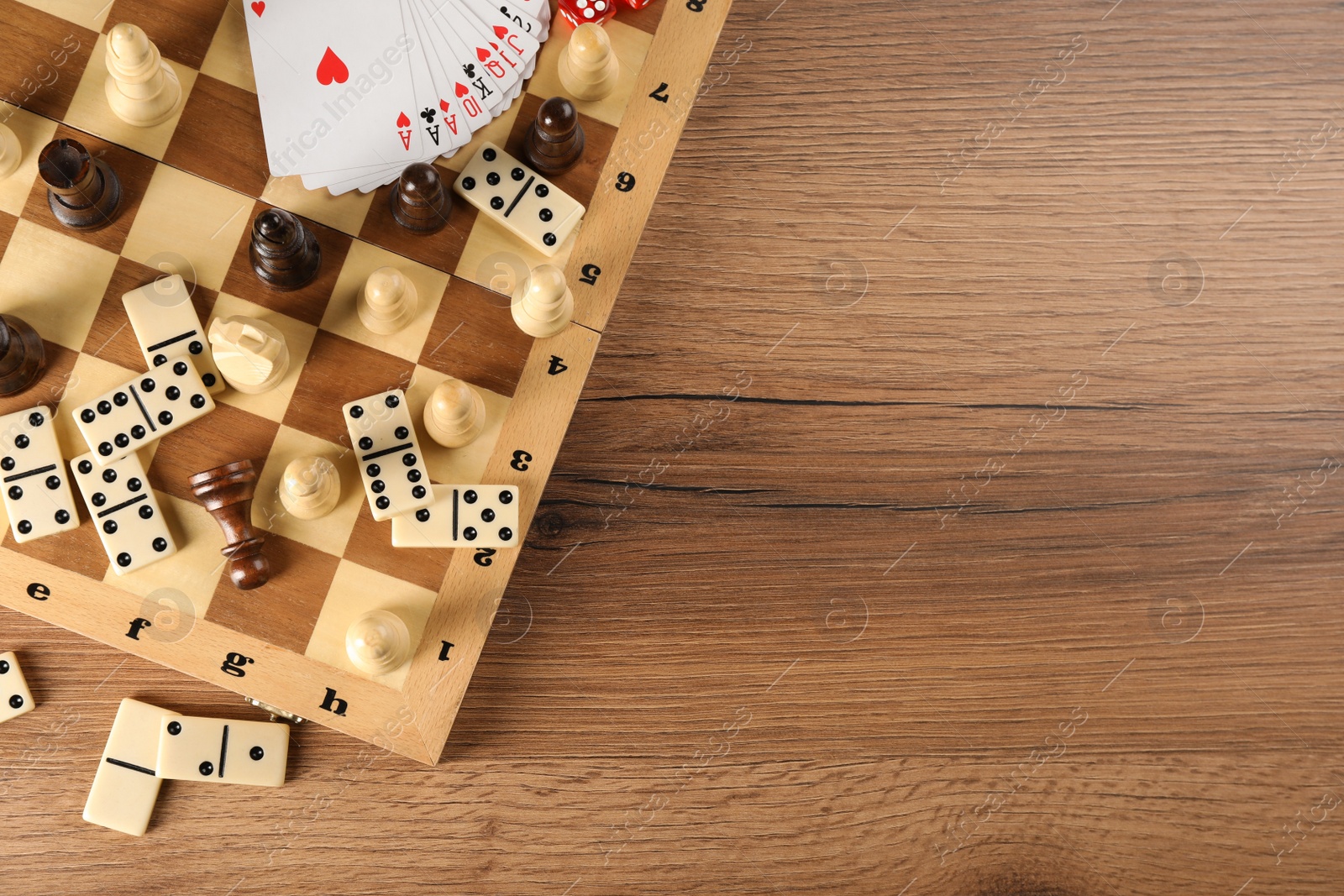 Photo of Elements of different board games on wooden table, flat lay. Space for text