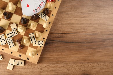 Elements of different board games on wooden table, flat lay. Space for text