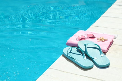 Photo of Beach accessories on wooden deck near swimming pool. Space for text