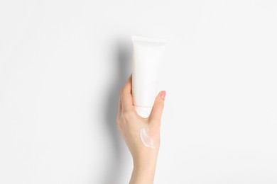 Photo of Woman with tube of cream on white background, closeup