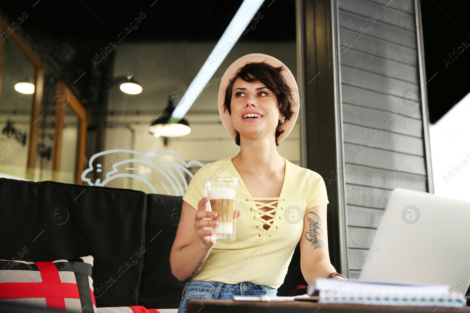 Photo of Young woman working with laptop at desk in cafe