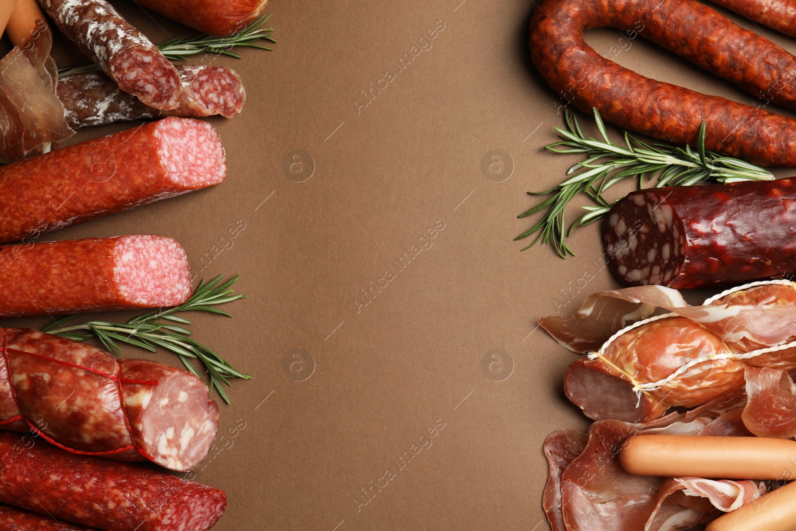 Photo of Frame made with different sausages on brown background, flat lay. Space for text