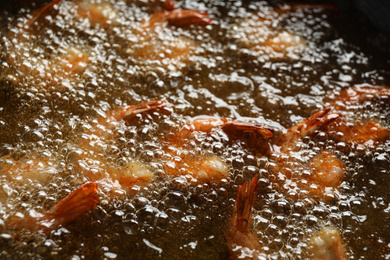 Photo of Cooking delicious shrimps in hot oil, closeup