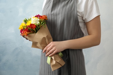 Photo of Woman holding bouquet with beautiful freesia flowers on color background, closeup