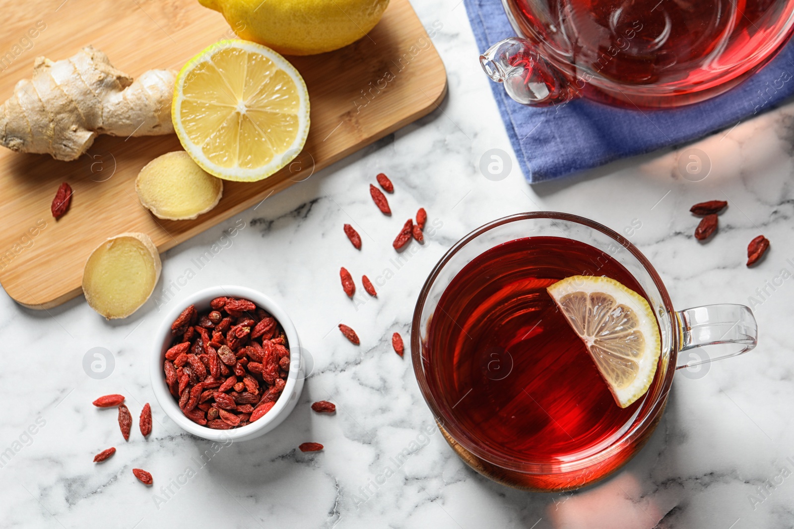 Photo of Flat lay composition with cup of healthy goji tea on marble table