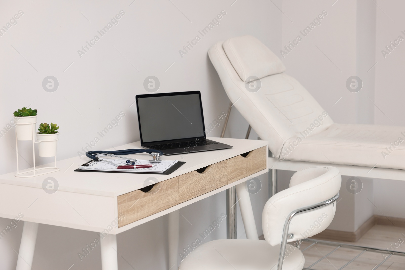 Photo of Modern medical office with doctor's workplace and examination table in clinic