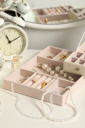 Photo of Jewelry boxes with many different accessories, perfume and alarm clock on white table