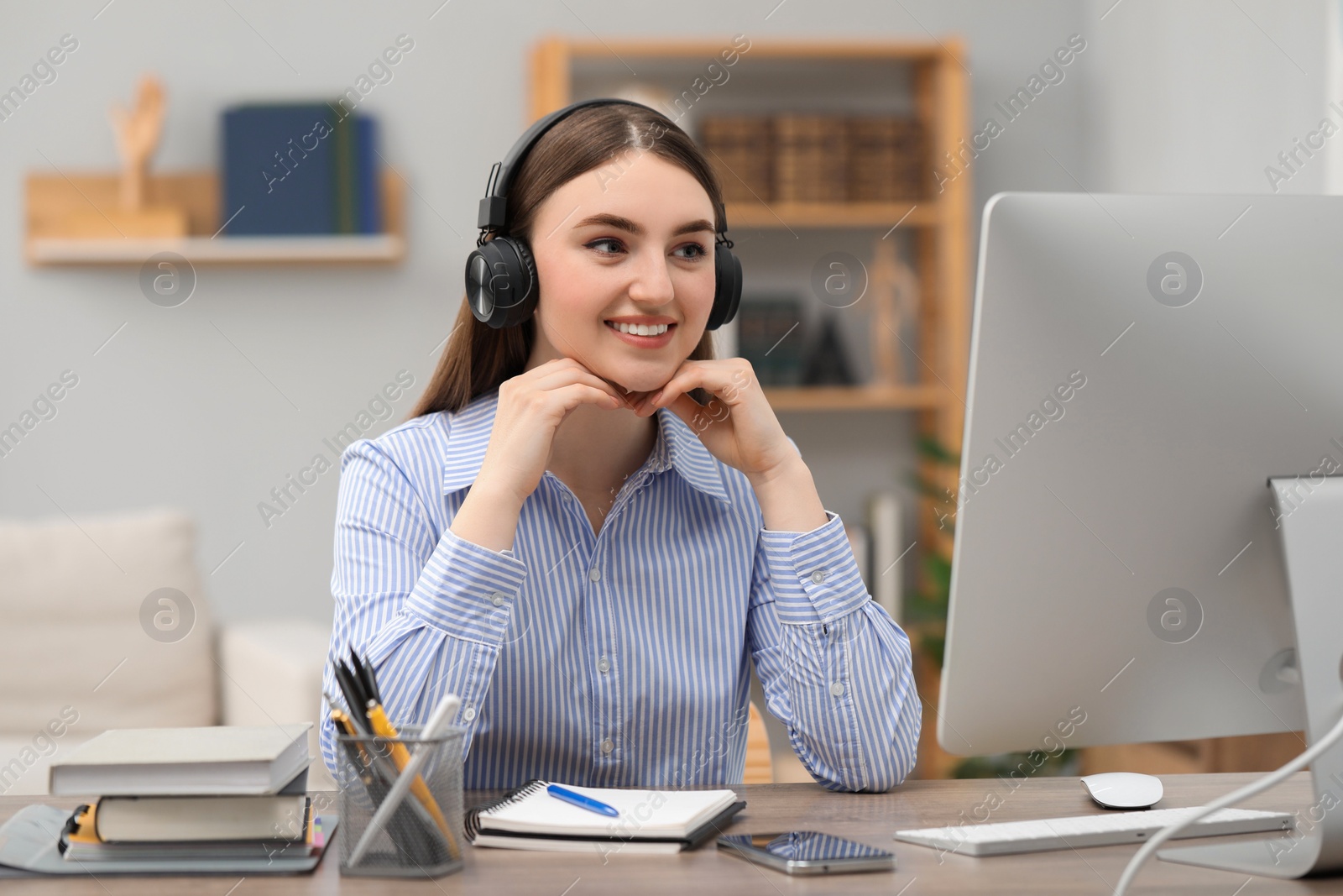 Photo of E-learning. Young woman using computer during online lesson at table indoors
