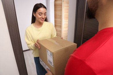 Photo of Woman receiving parcel from courier at home
