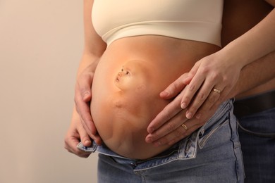 Image of Man, pregnant woman and baby on beige background, closeup view of belly. Double exposure
