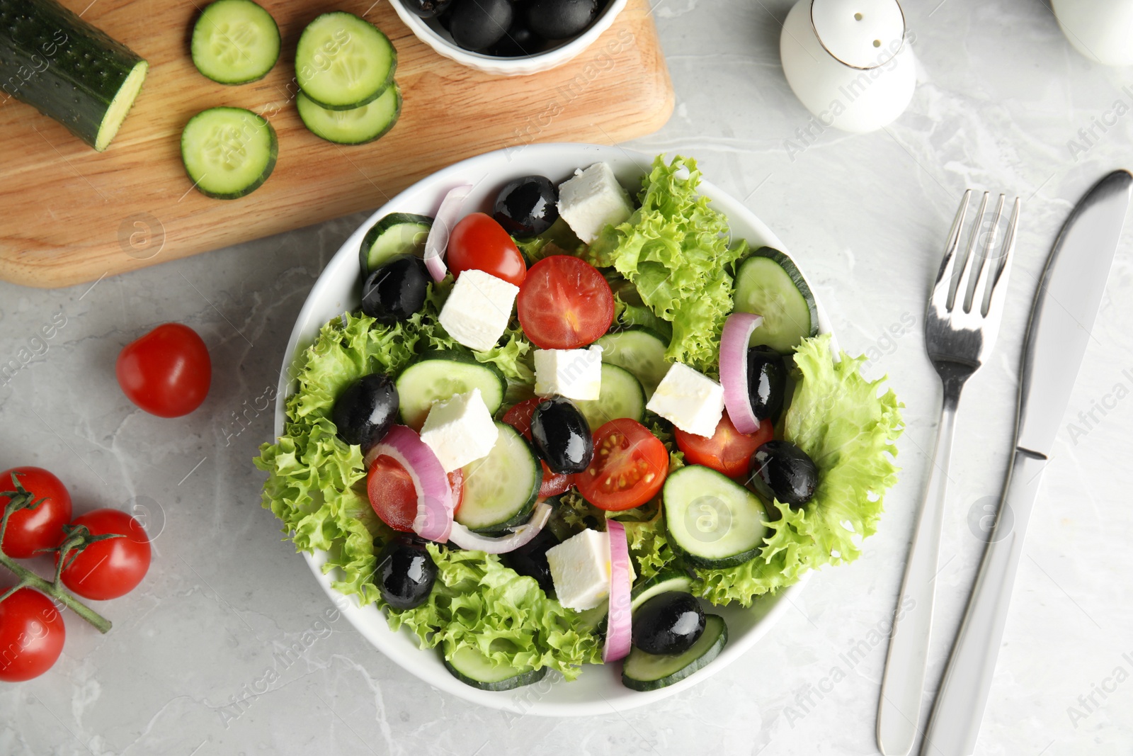 Photo of Tasty fresh Greek salad on grey marble table, flat lay