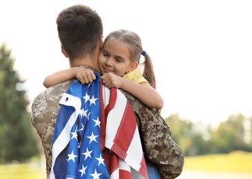 Father in military uniform with American flag and his daughter at sunny park