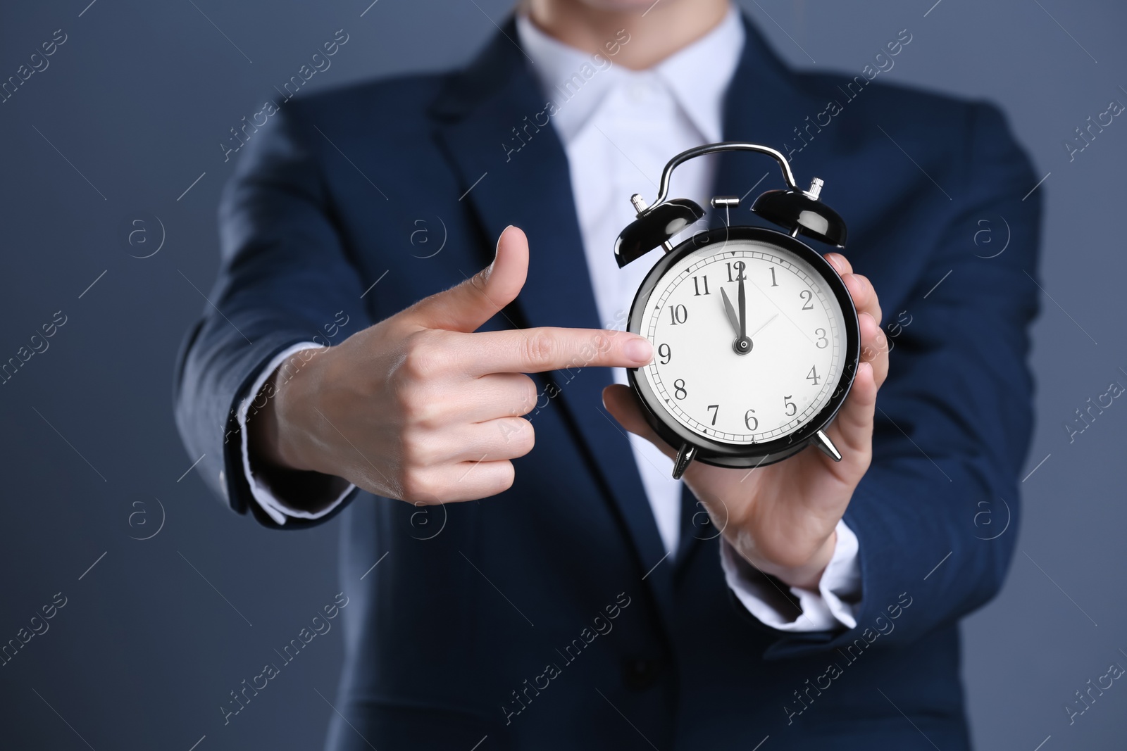 Photo of Businesswoman holding alarm clock on color background. Time concept