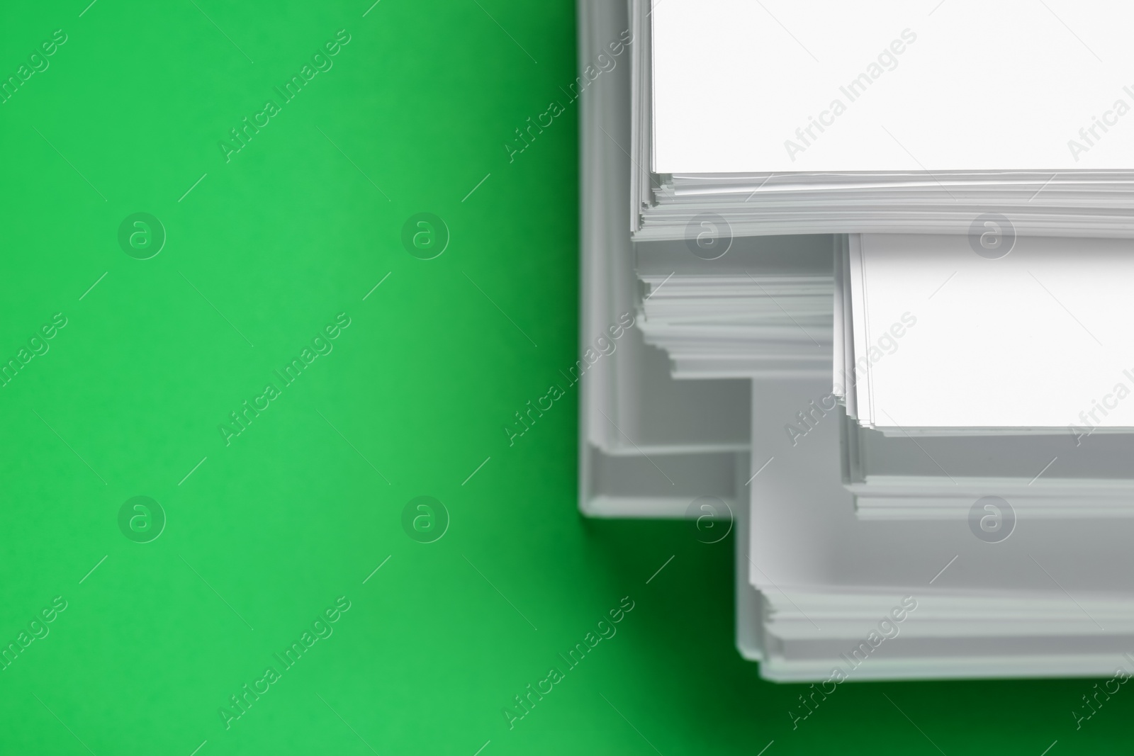 Photo of Stack of white paper on green background, closeup. Space for text