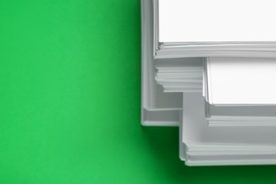 Photo of Stack of white paper on green background, closeup. Space for text