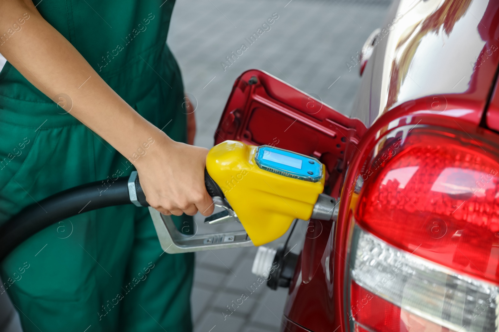 Photo of Young worker refueling car at modern gas station, closeup