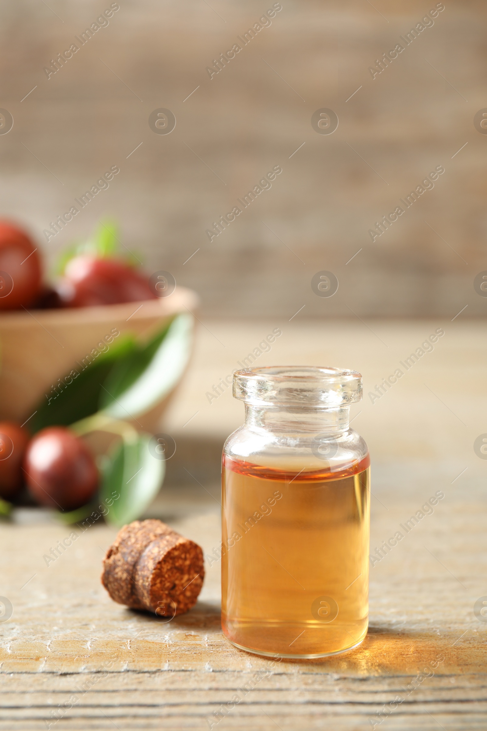 Photo of Glass bottle with jojoba oil on wooden table