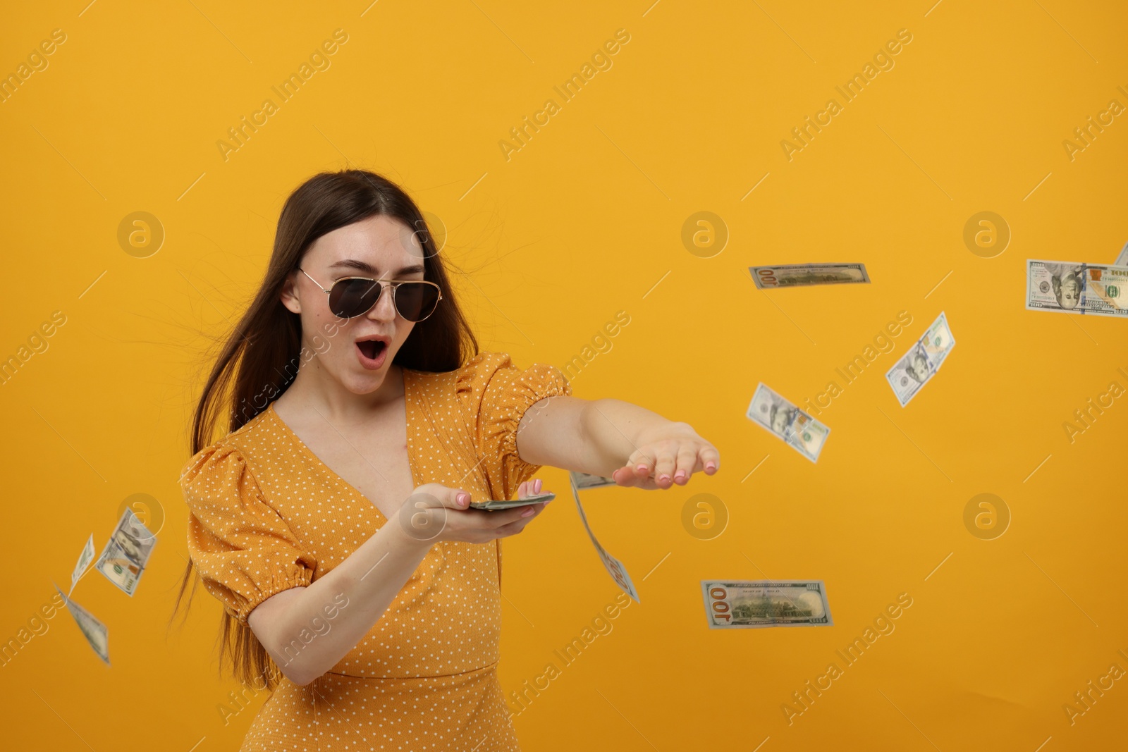 Photo of Happy woman throwing money on orange background