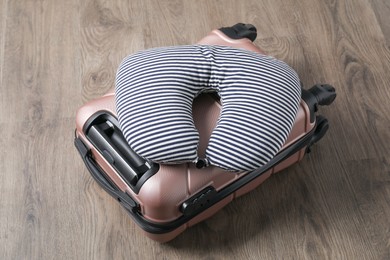 Striped travel pillow and suitcase on floor