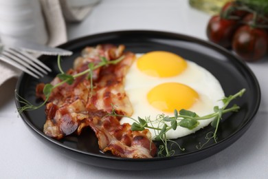 Fried eggs and bacon served on white table, closeup