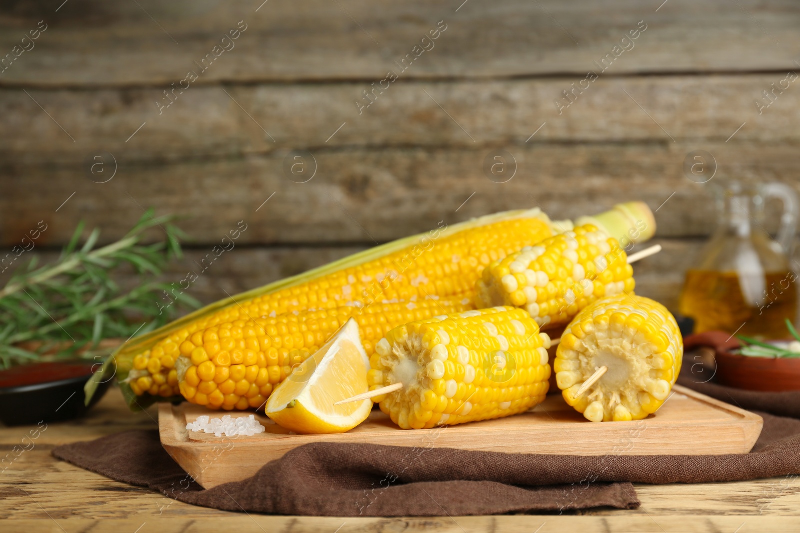 Photo of Tasty corn cobs and lemon on wooden table