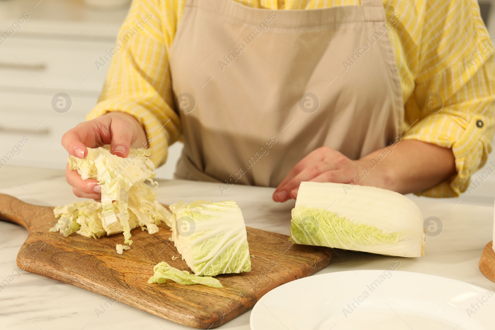 Photo of Woman with cut Chinese cabbage at white kitchen table, closeup