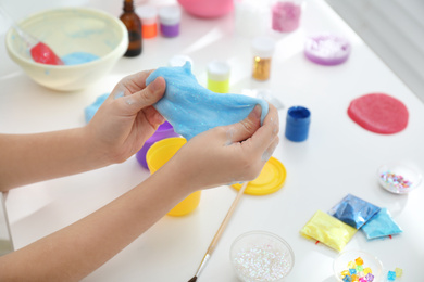 Little girl making DIY slime toy at table, closeup