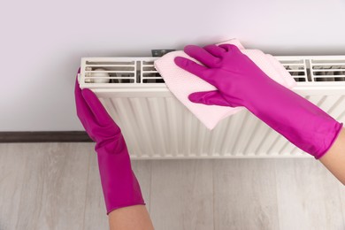 Photo of Woman cleaning white radiator with rag indoors, above view