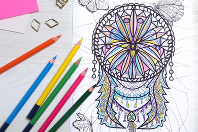 Photo of Antistress coloring page and pencils on white wooden table, flat lay