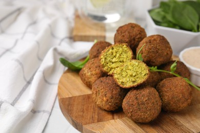 Photo of Delicious falafel balls, herbs and sauce on table