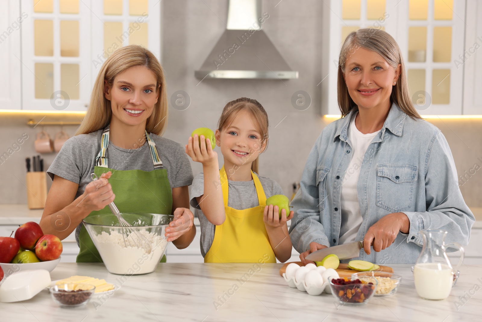 Photo of Three generations. Happy grandmother, her daughter and granddaughter cooking together in kitchen