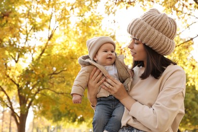 Photo of Happy mother with her baby son in park on autumn day, space for text