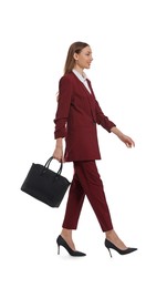 Photo of Young woman in burgundy suit with black bag walking on white background