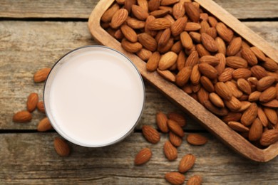 Glass of almond milk and almonds on wooden table, top view