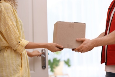 Photo of Woman receiving parcel from deliveryman on blurred background, closeup. Space for text