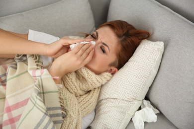 Photo of Sick woman lying on sofa at home. Influenza virus