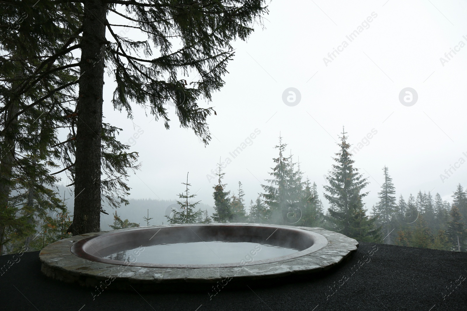 Photo of Hot tub with beautiful view on coniferous forest on winter day