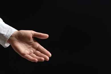 Photo of Woman holding something in hand on black background, closeup. Space for text