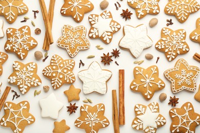 Tasty Christmas cookies with icing and spices on white background, flat lay