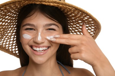 Teenage girl applying sun protection cream on her face against white background, closeup