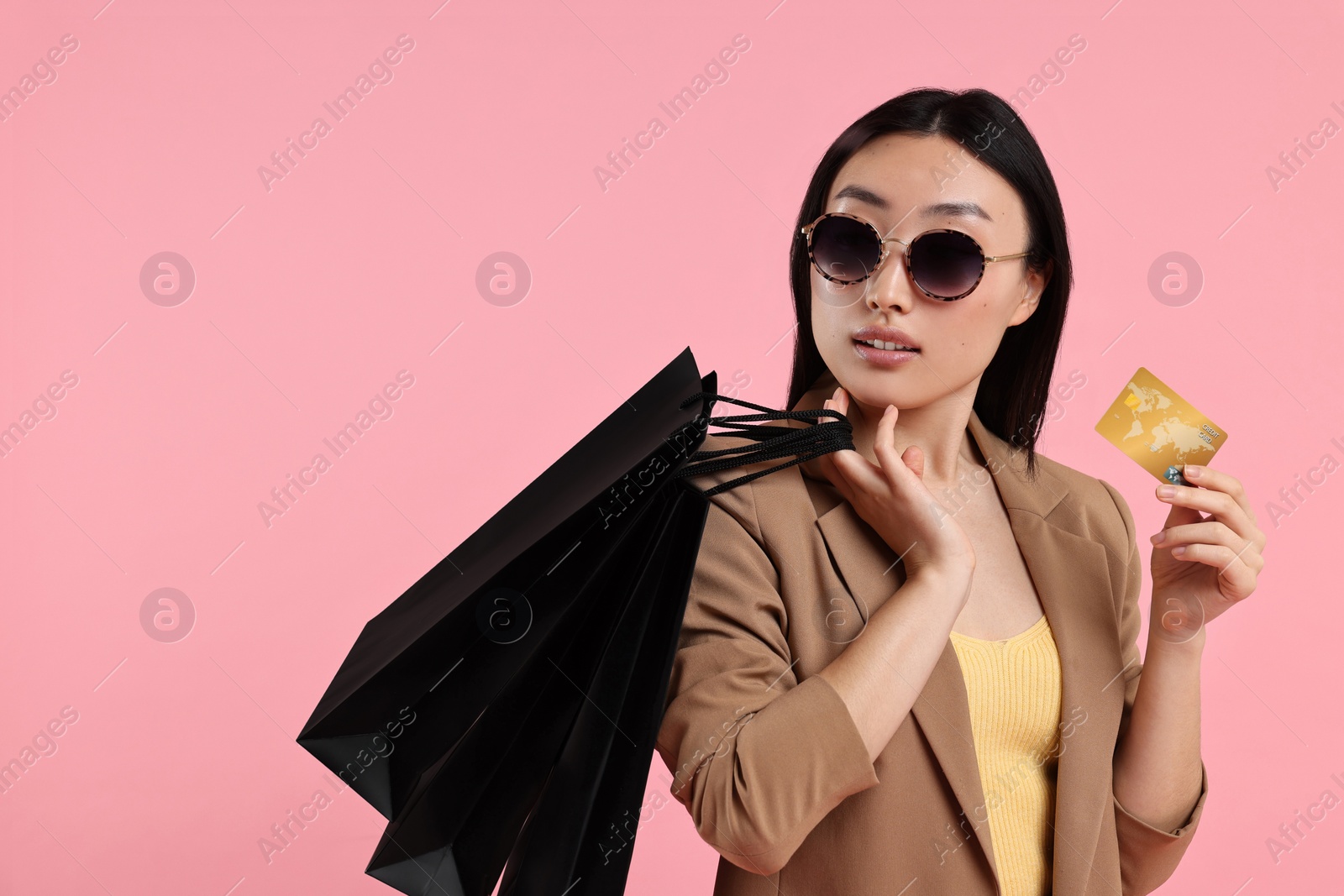 Photo of Beautiful woman with shopping bags and credit card on pink background. Space for text