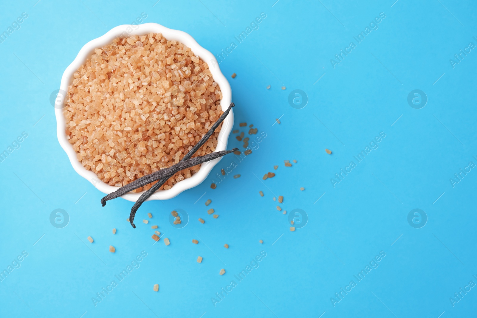 Photo of Bowl with brown vanilla sugar on color background, top view